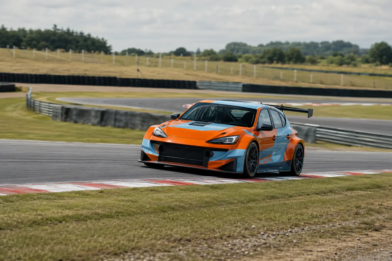 Orange and ice blue race car graphics on a touring car clipping a circuit kerb