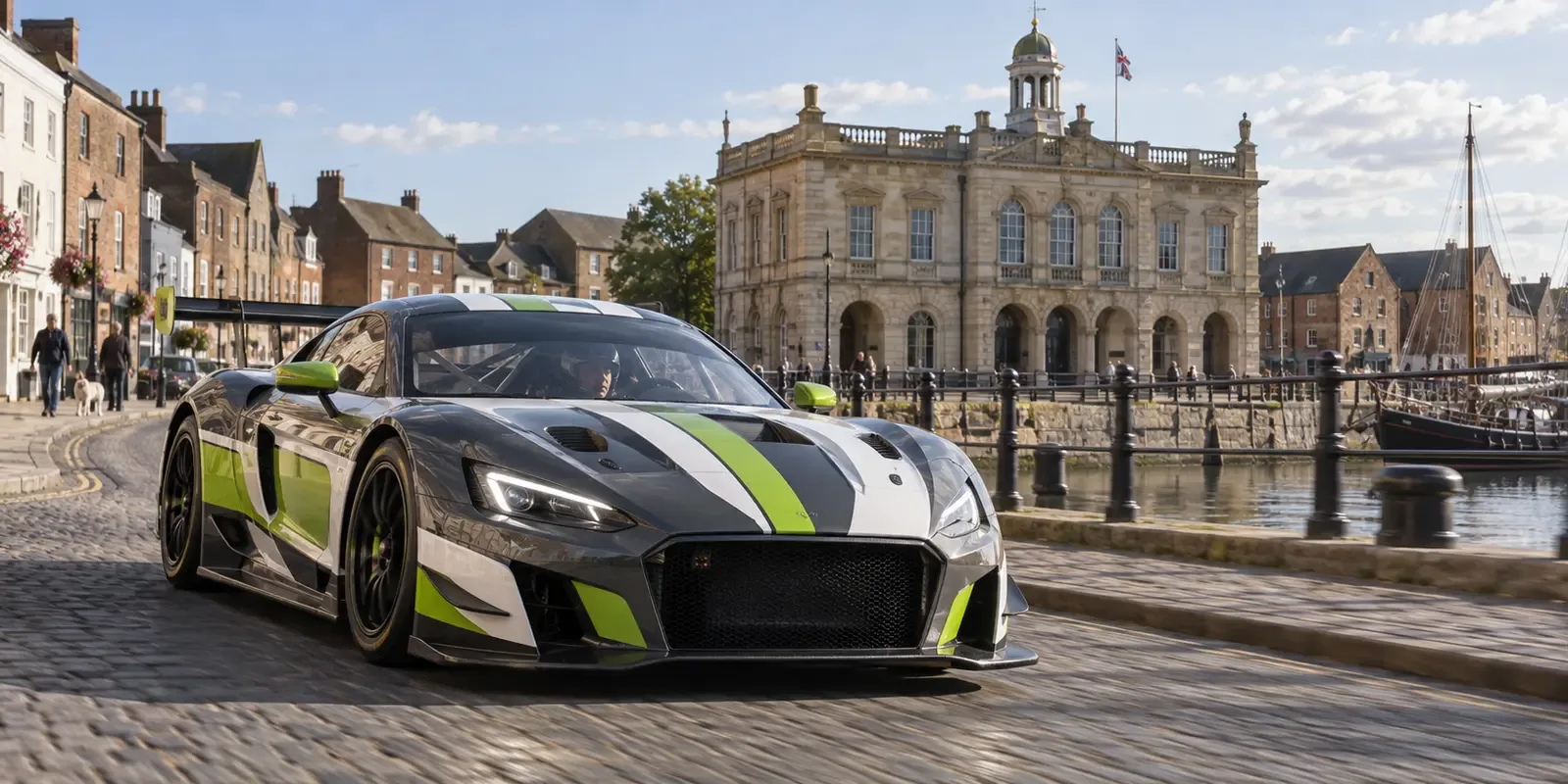 Race-liveried GT car travelling past the historic King's Lynn quayside