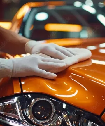 Detailer finishing the polished bonnet of an orange car during ceramic coating preparation